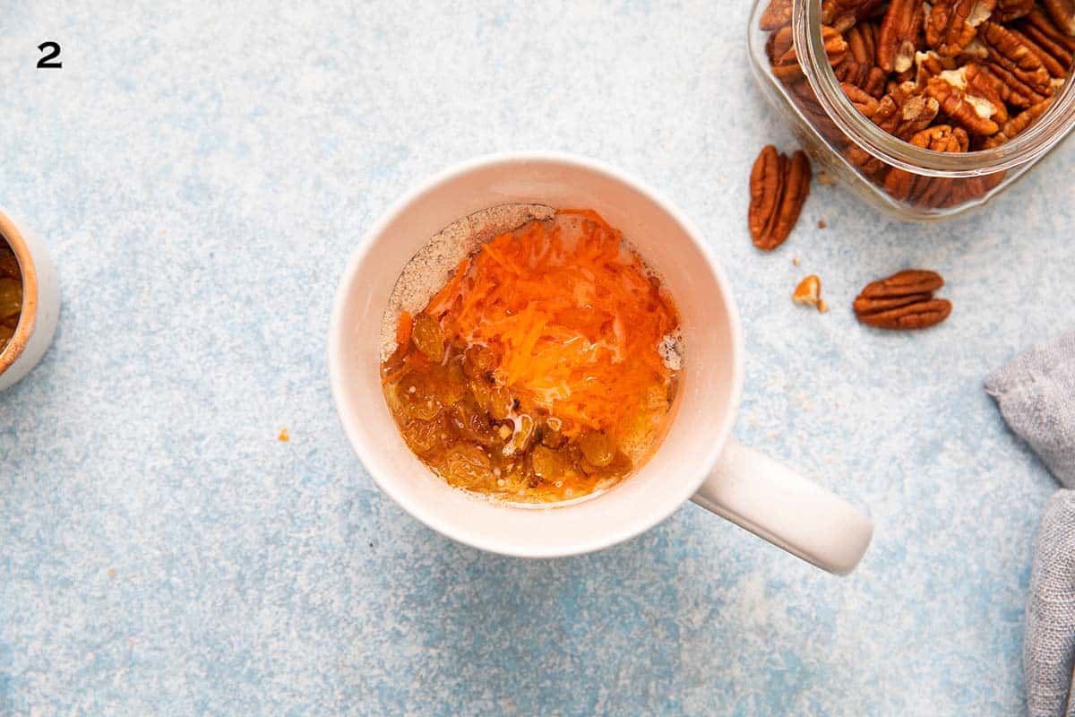 white coffee mug with grated carrot and raisins. 
