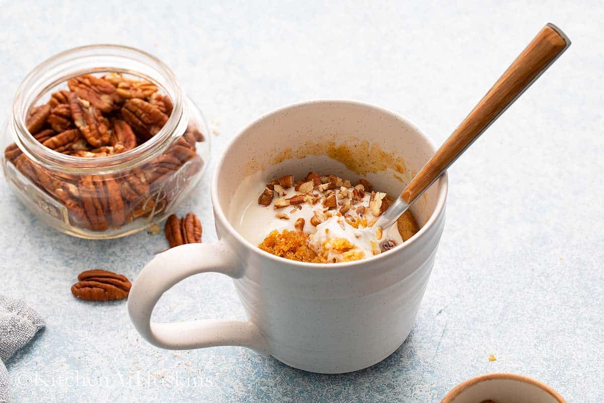 cup with carrot cake along with a spoon.