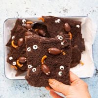 a hand holding a piece of hallowen chocolate bark.