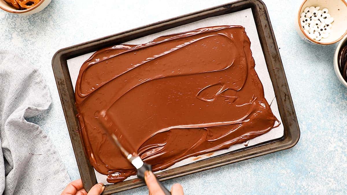 spreading melted chocolate on a baking sheet.