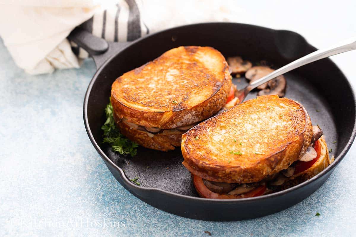 2 cooked mushroom grilled cheese on a skillet along with a spatula.