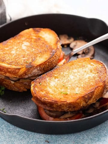 Cooked mushroom sandwiches on a cast iron skillet.