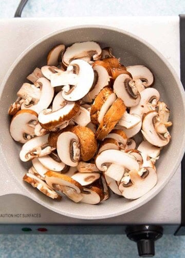 sliced mushrooms in a small white skillet.