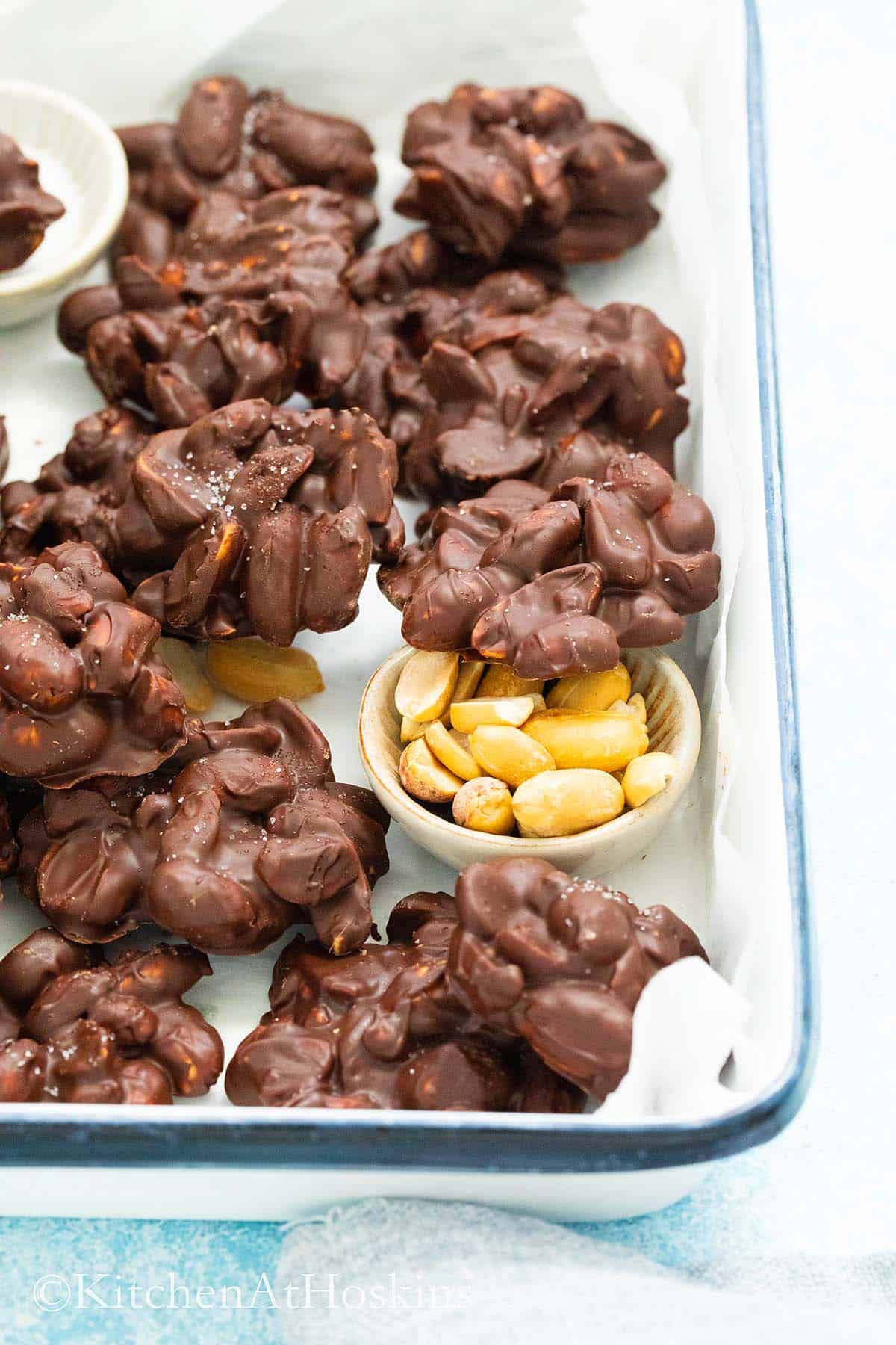 white metal tray filled with chocolate peanut cluster candy.