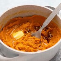mashed sweet potatoes in a pot topped with butter.