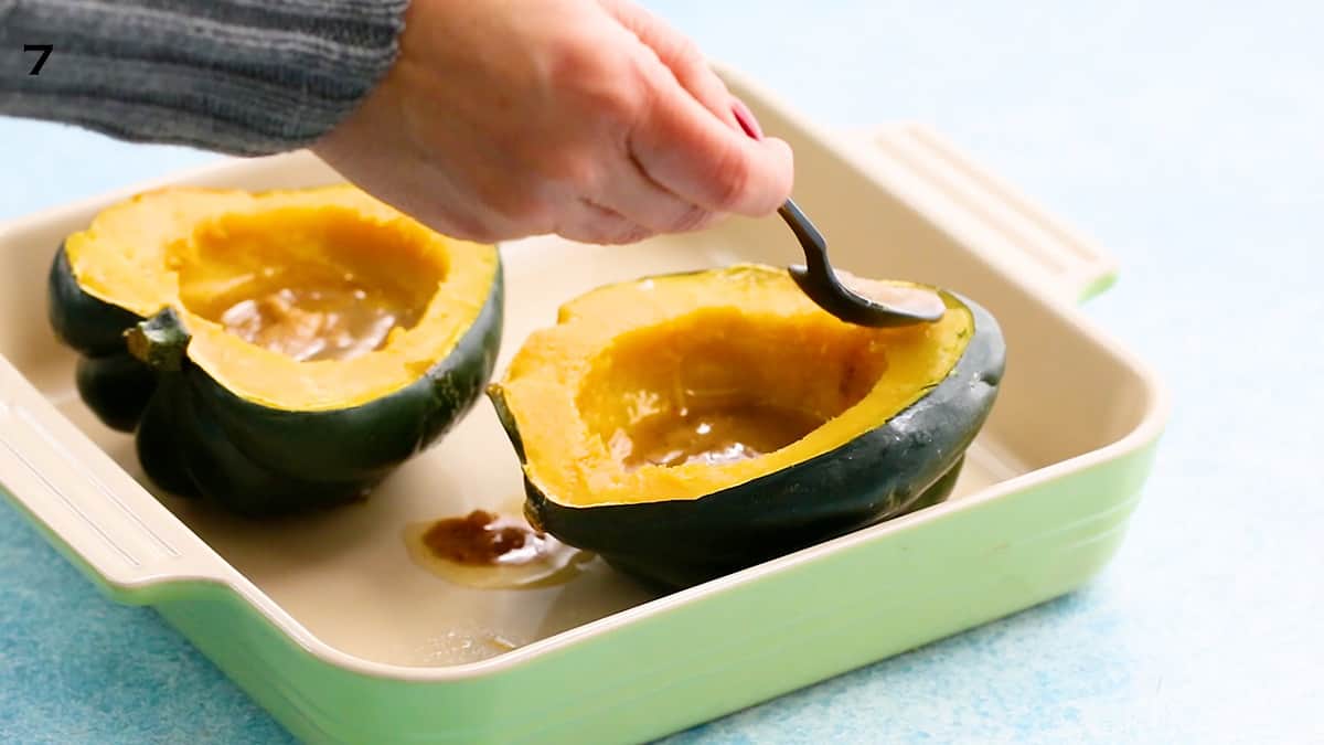 a hand drizzling sweet butter over a cooked acorn squash half.