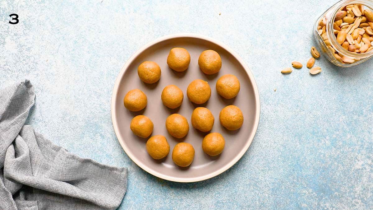 rolled peanut butter almond balls placed in a round grey plate.