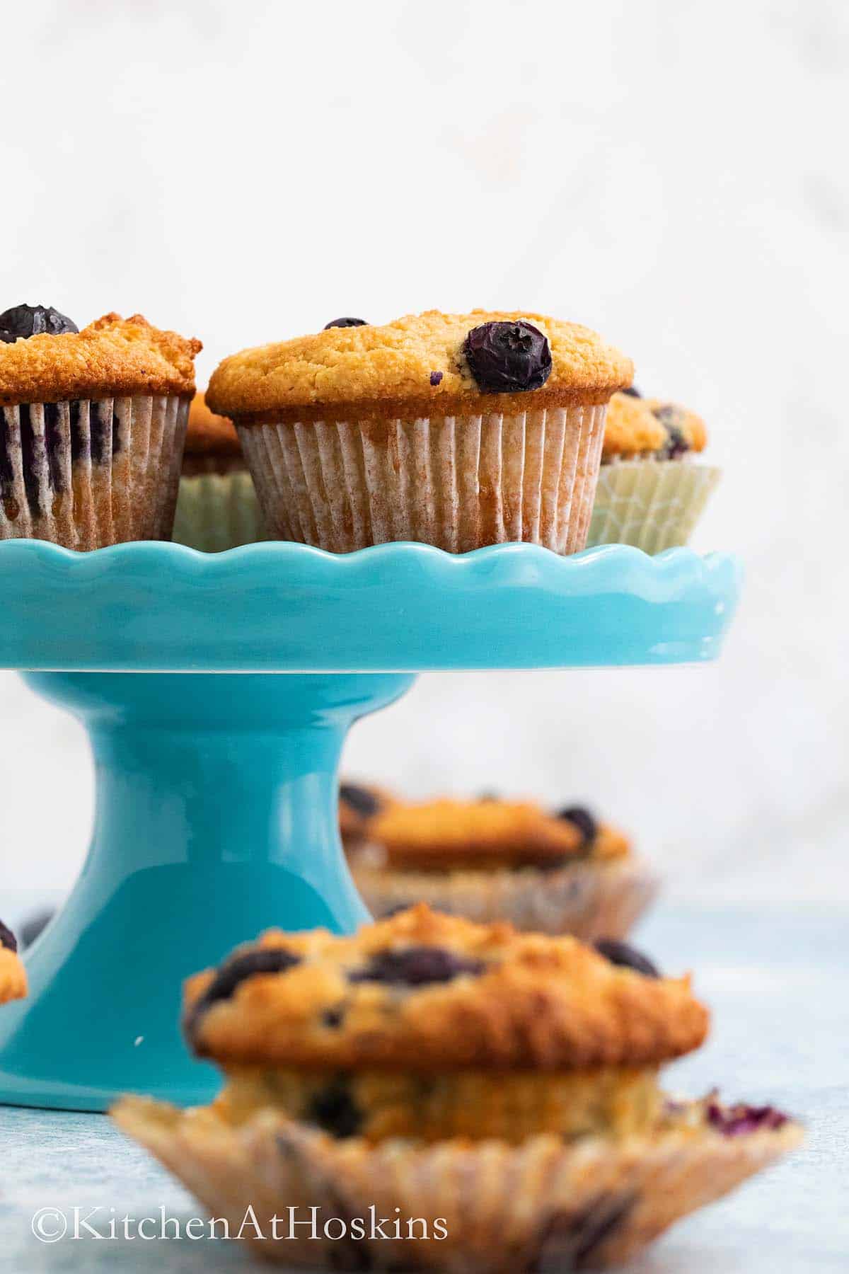 baked blueberry muffins on a blue cake stand.