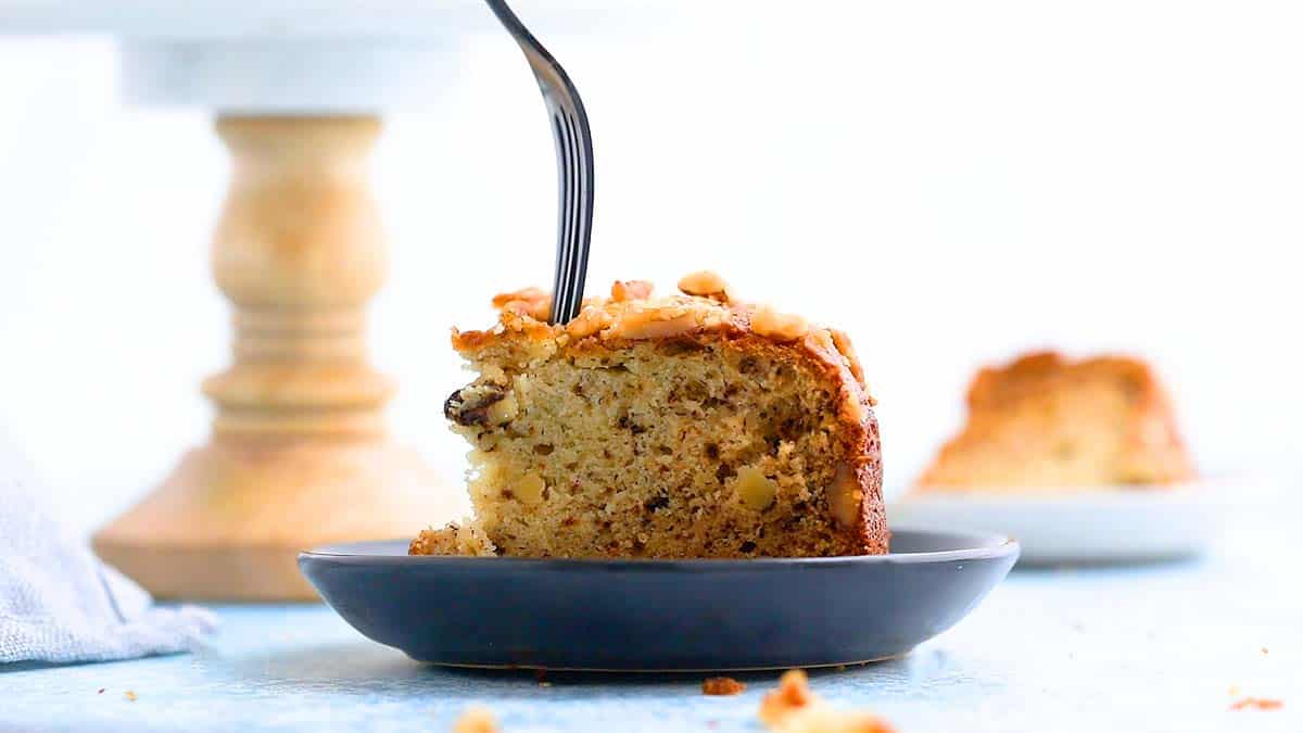 a slice of banana cake on a green plate with a fork.