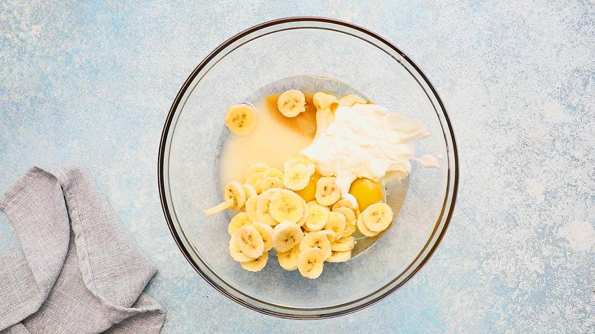 glass bowl with sliced bananas, sour cream and sugar.