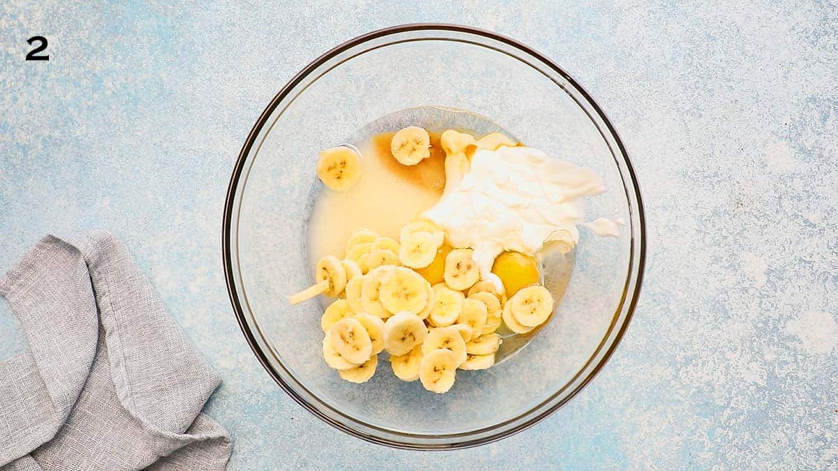 glass bowl with yogurt, sugar, eggs and sliced bananas.