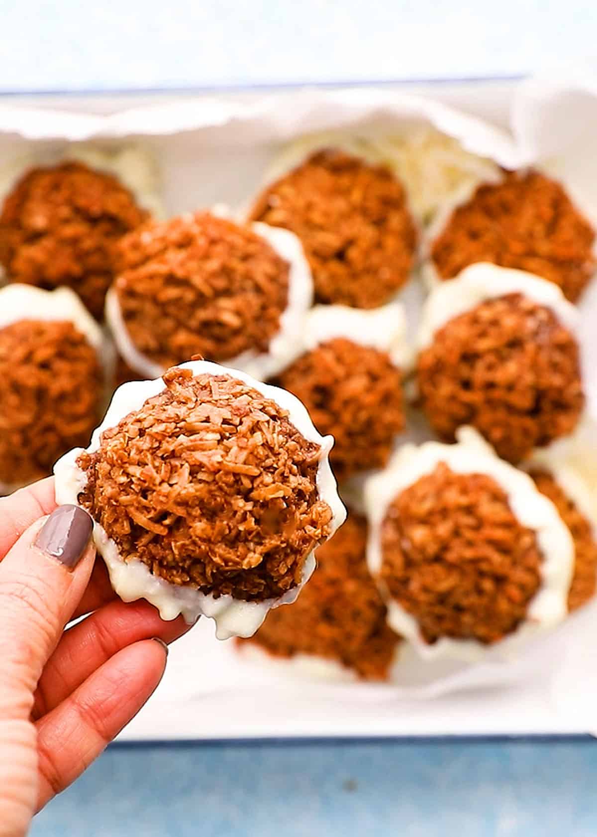 a hand holding one chocolate coconut macaroon.