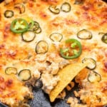 a chip scooping jalapeno dip from a skillet.