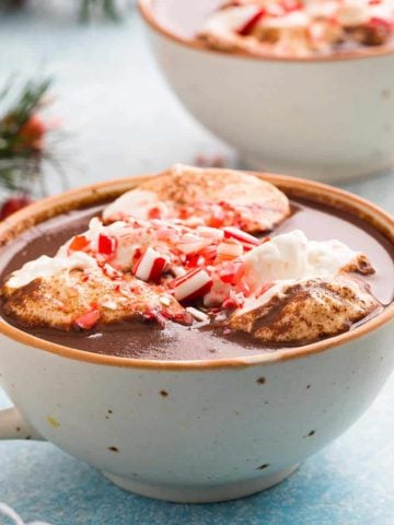 cup with hot chocolate topped with whipped cream & candy canes.