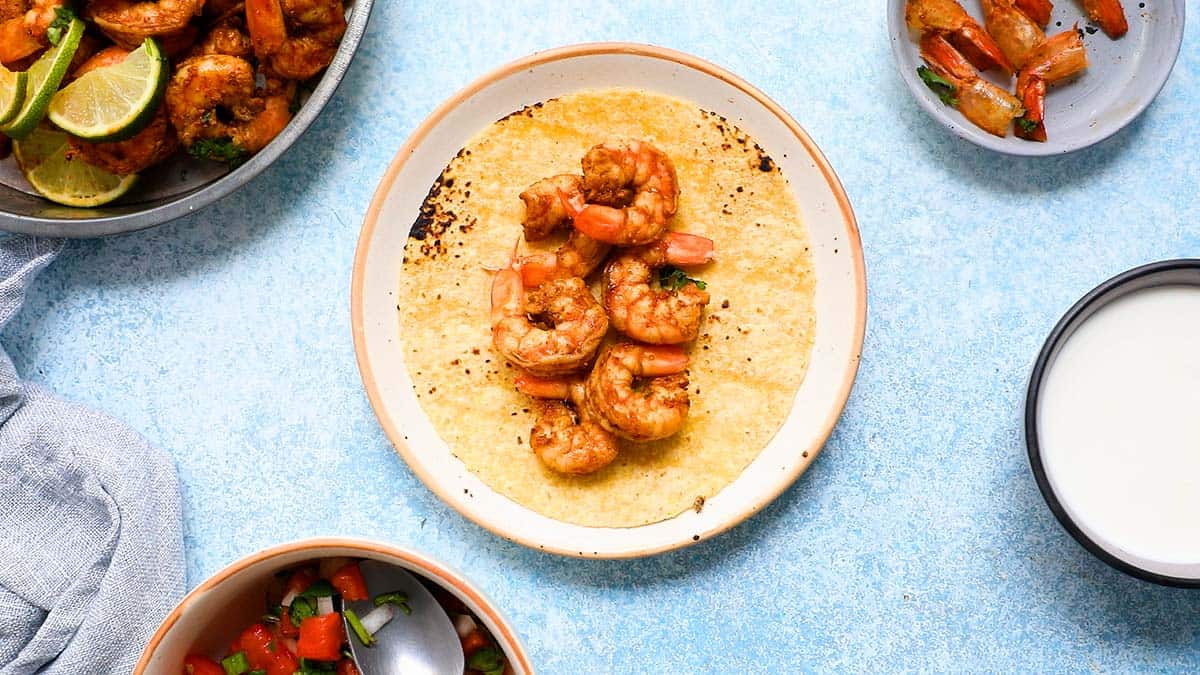 tortilla with cooked shrimp placed on a plate.