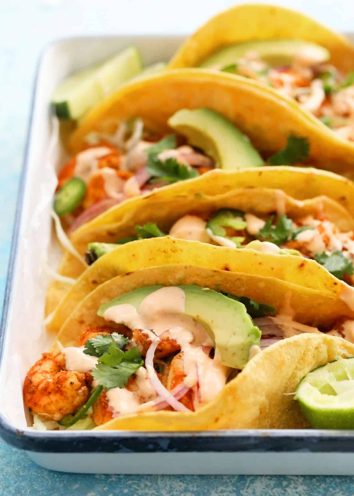assembled shrimp tacos in a white tray.