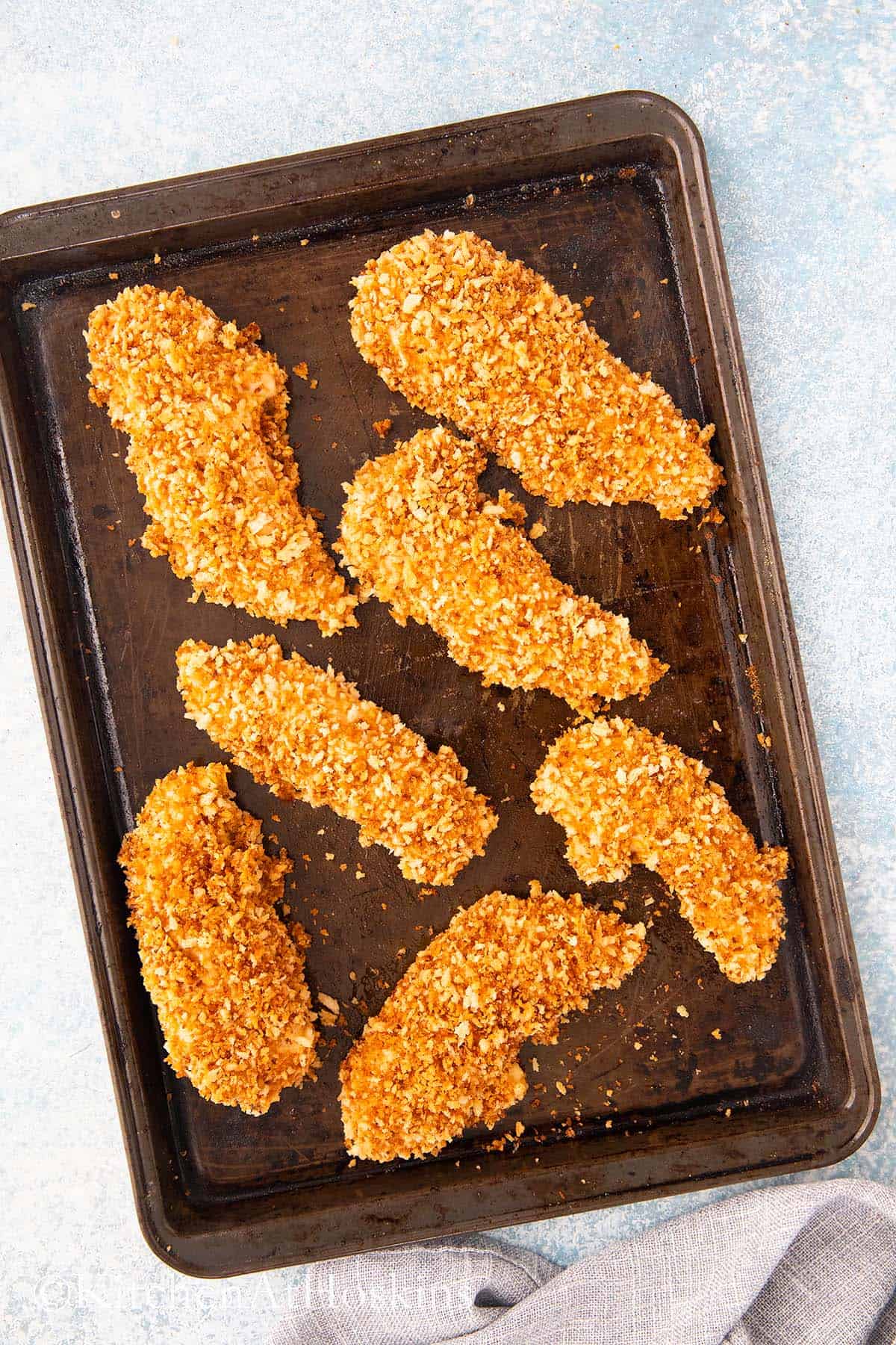 panko breaded chicken tenders on a baking sheet.