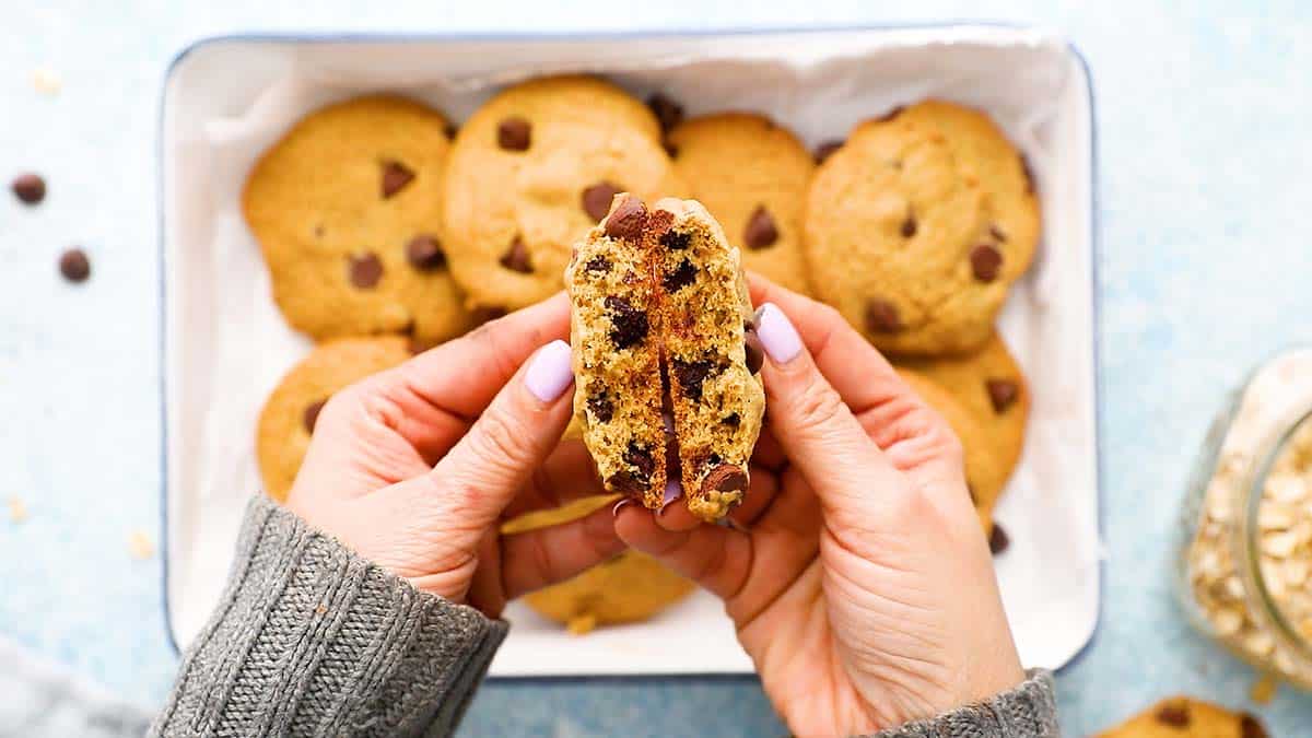 2 hands with a broken oat flour chocolate chip cookie.