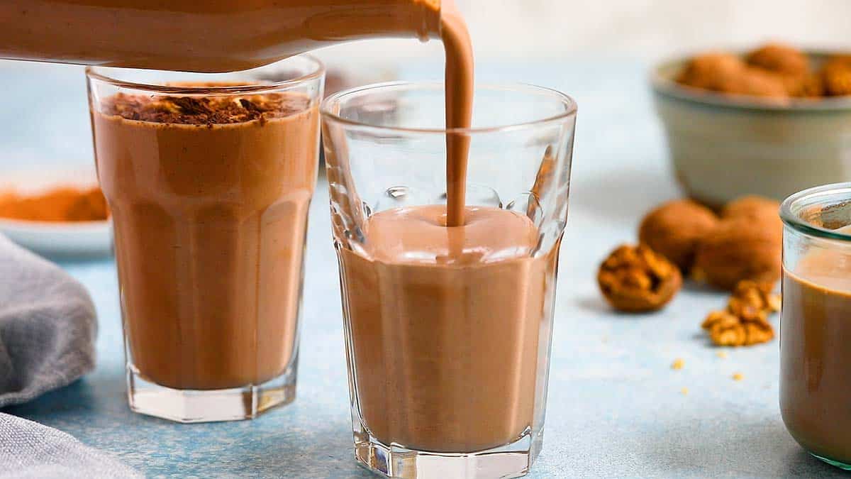 pouring chocolate date smoothie into a glass.