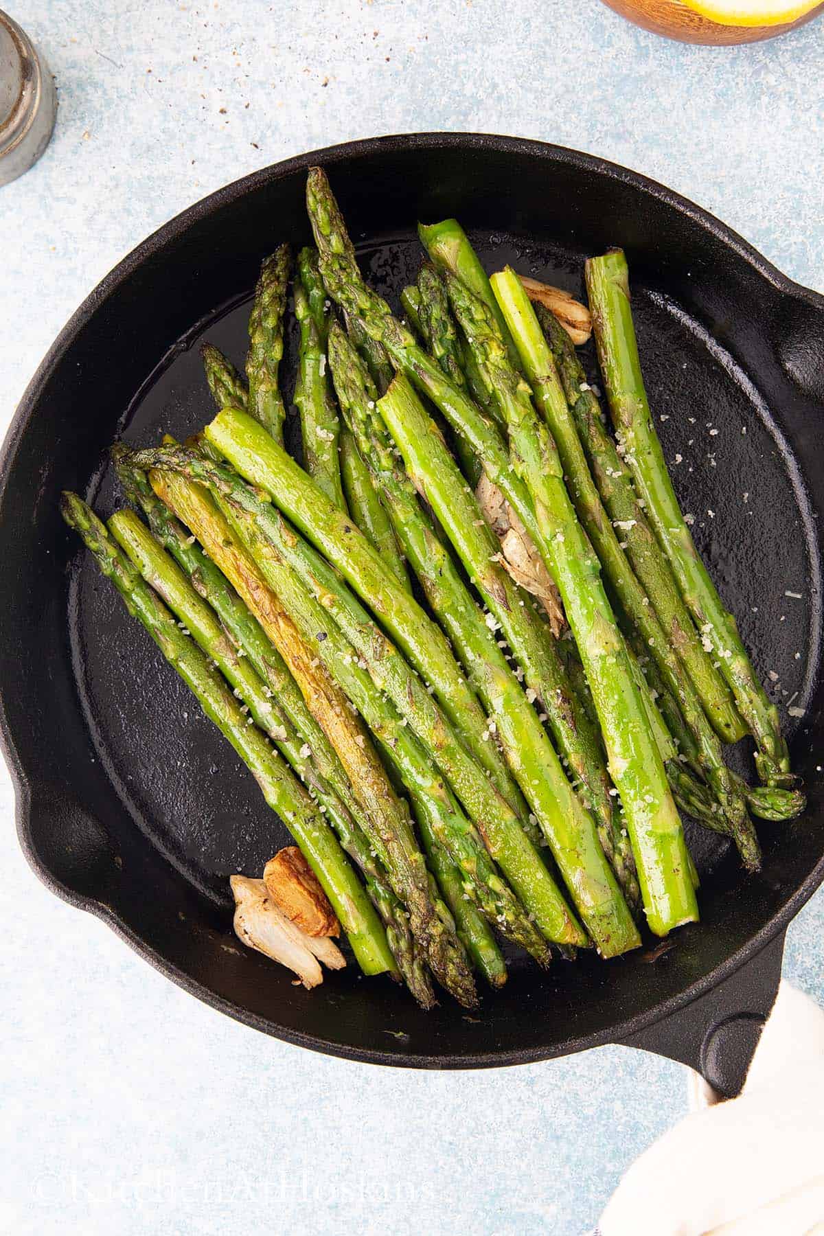 black skillet with cooked asparagus.