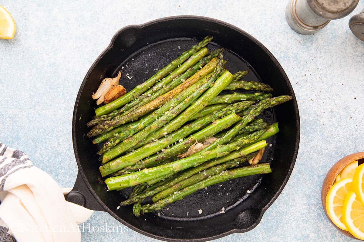 black skillet with cooked aspargus.