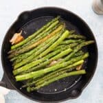 black skillet with cooked aspargus.