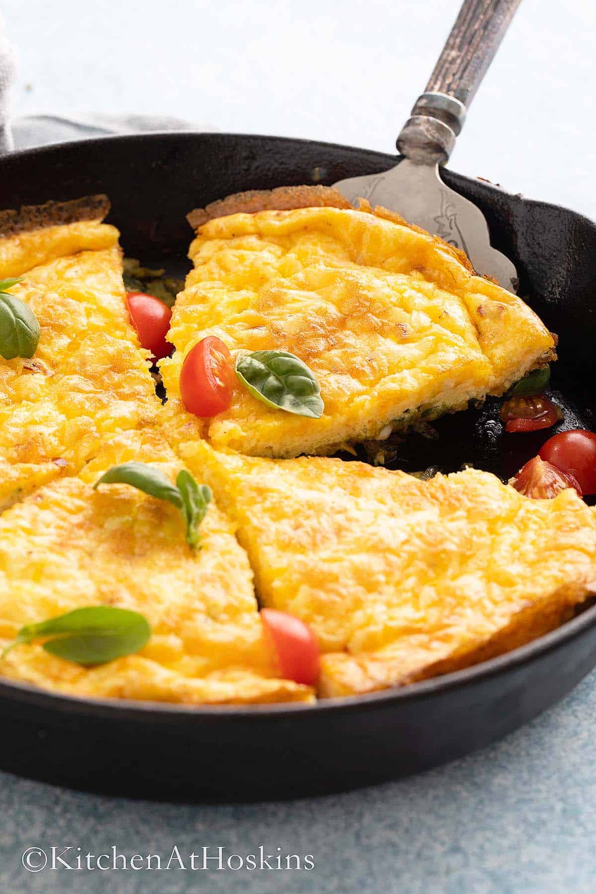 baked yellow fritatta in a black skillet.