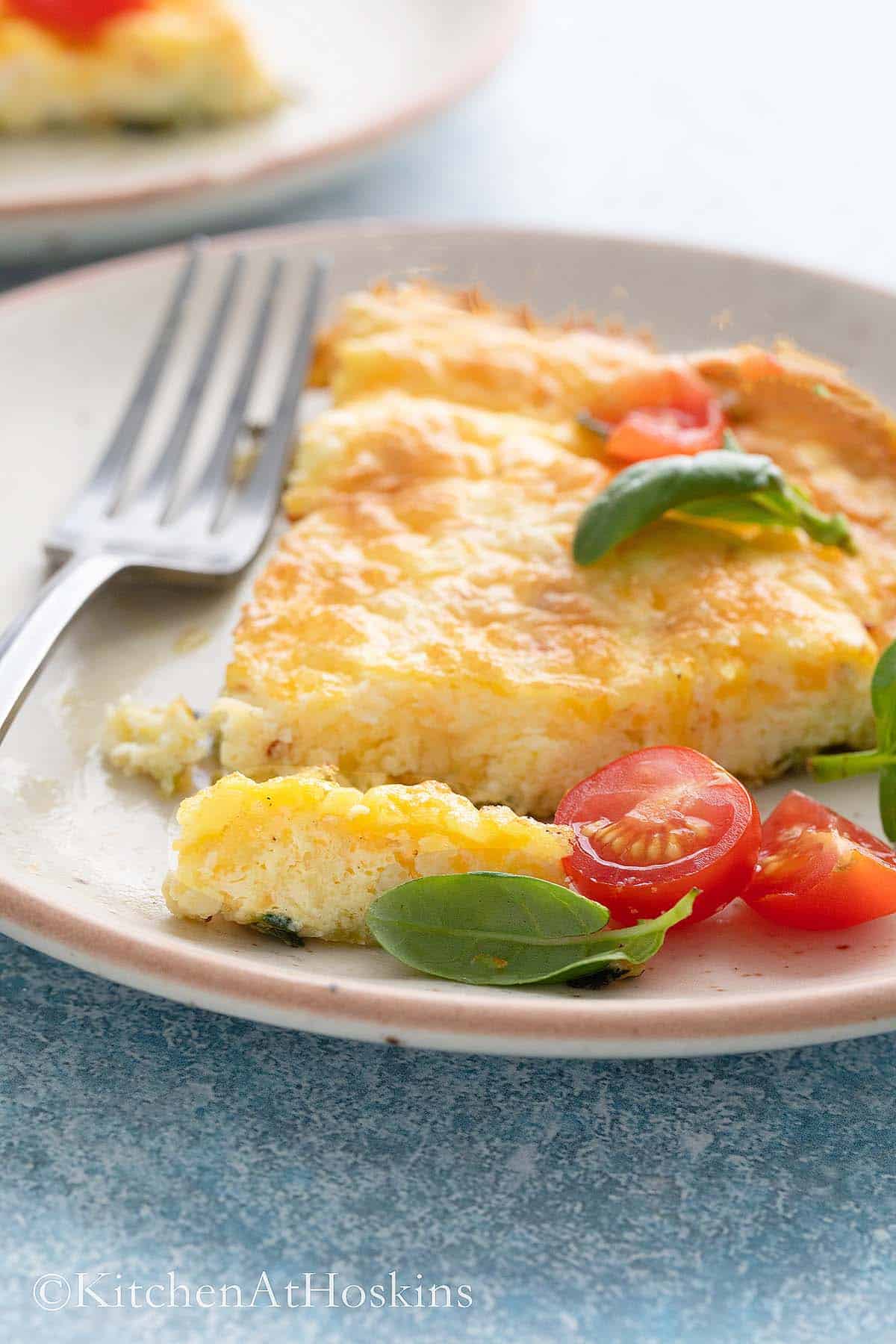 white plate with a slice of egg frittata and fork.