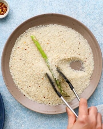 one green asparagus in white breadcrumbs in a large brown plate.