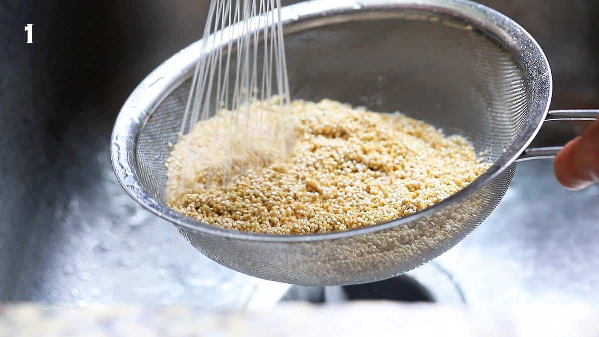 a strainer filled with quinoa under running water.