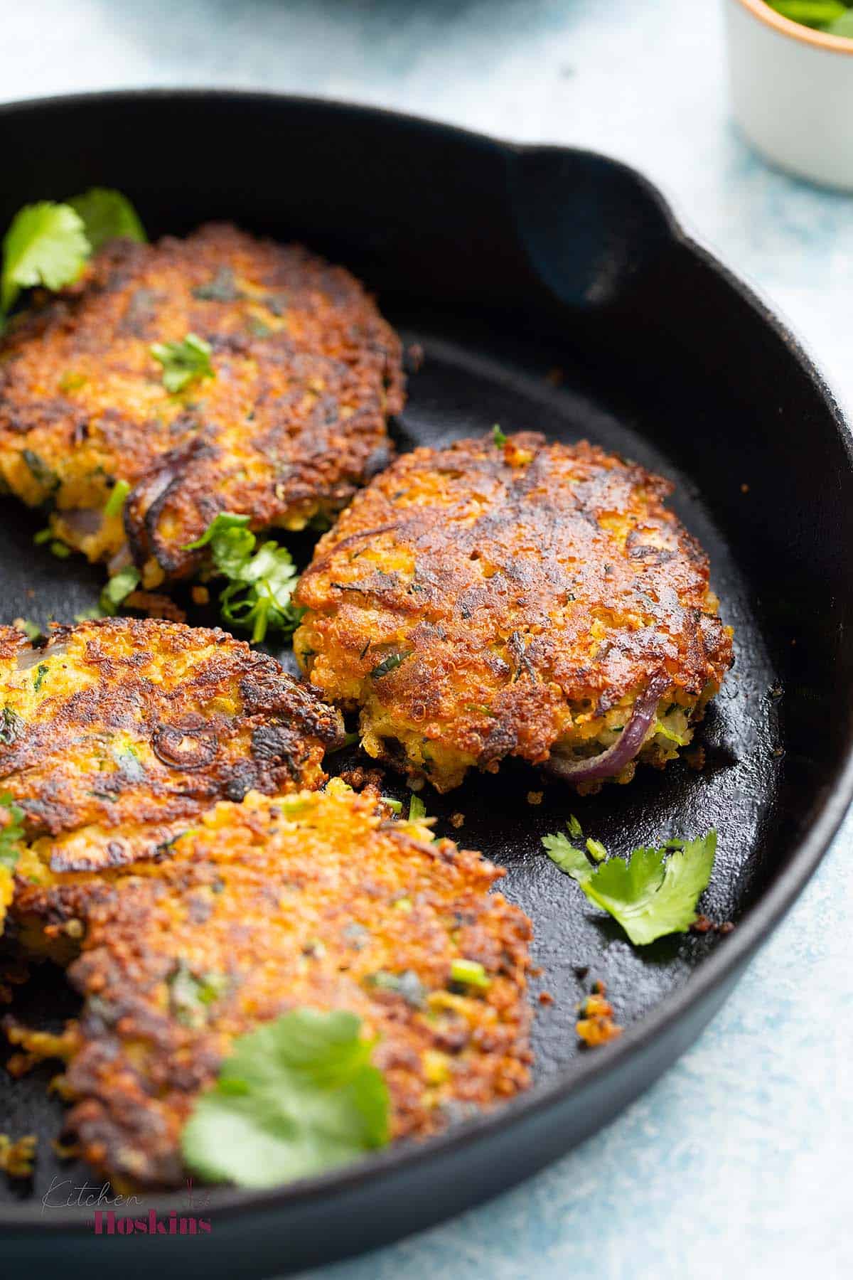 4 zucchini fritters in a black skillet. 
