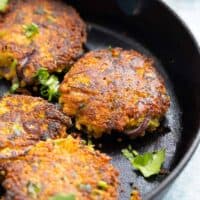cooked 4 zucchini fritters in a black cast iron pan.