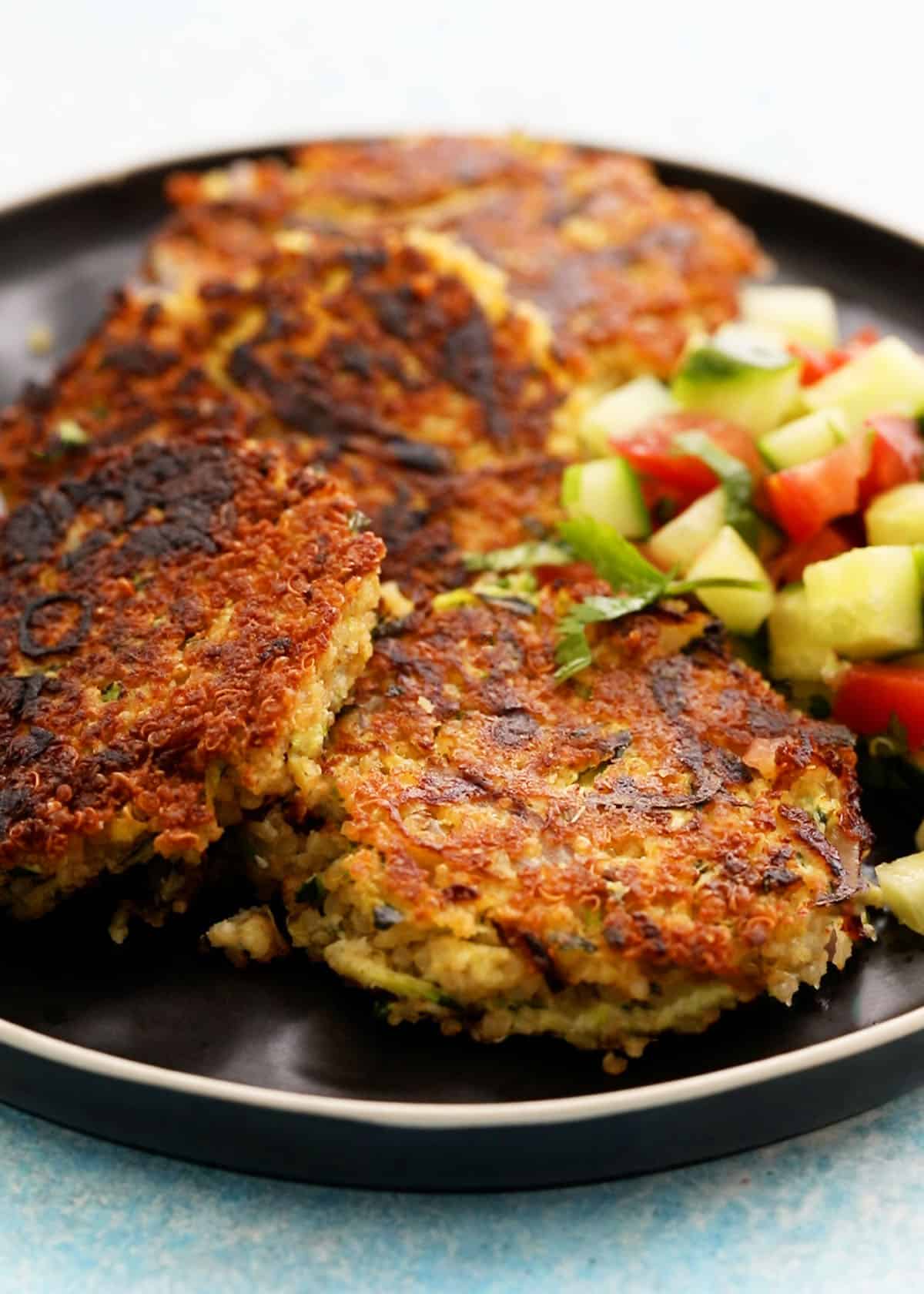 4 zucchini fritters placed in a black plate.