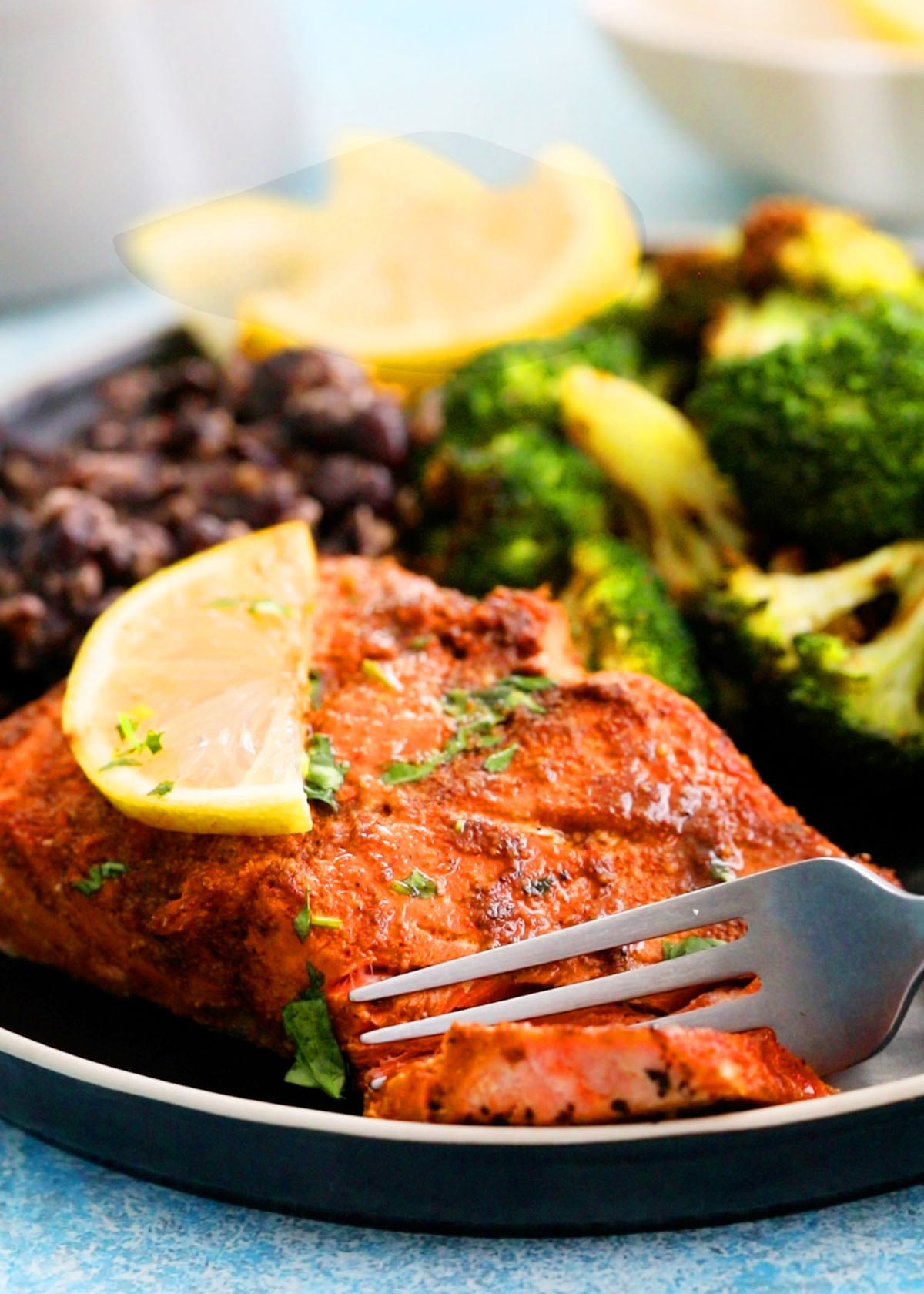 air fried salmon with green broccoli in a black plate.