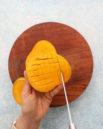 two hands cutting a mango.