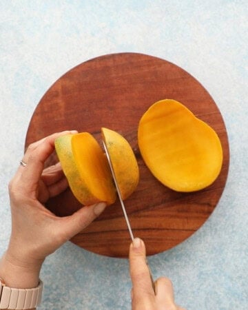 two hands cutting a mango.