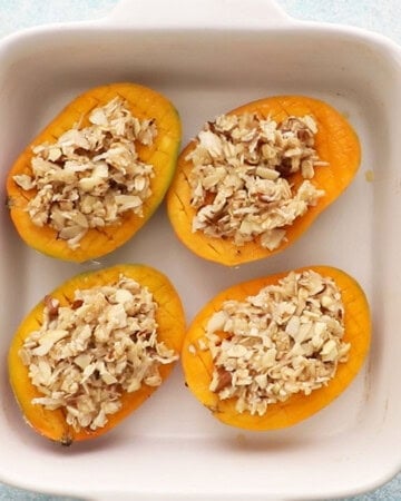 4 cut mangoes in a white baking dish.