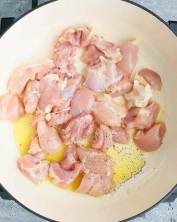 chopped chicken cooking in a white pan.