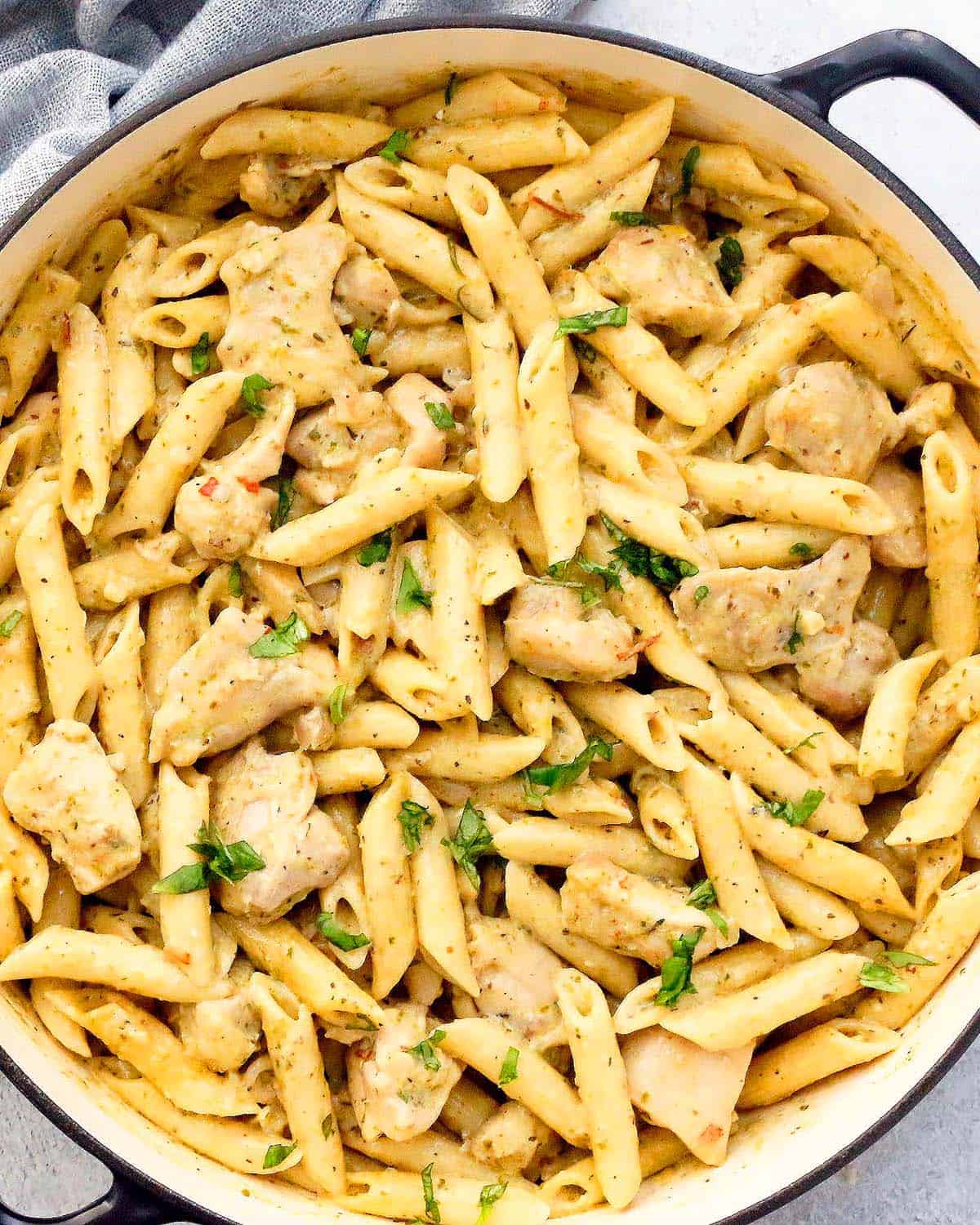 yellow pasta with chicken in a white pan.