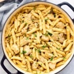 yellow pasta with chicken in a white pan.
