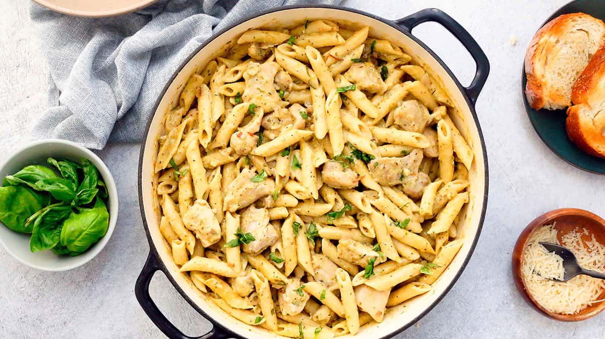 yellow pasta with chicken in a white pan.