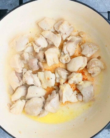chopped chicken cooking in a white pan.