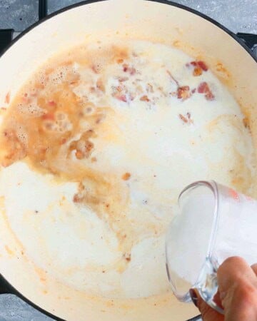 a hand pouring white milk into a white pan.