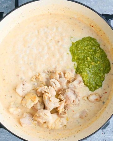 white milk, chicken and green pesto in a white pan.
