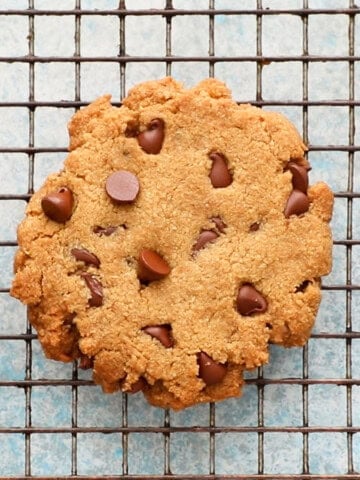 one chocolate chip cookie on a wire rack.