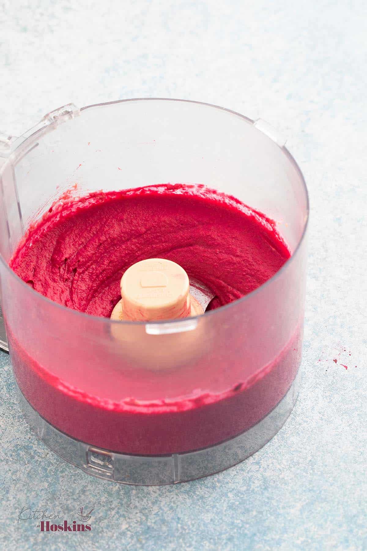 a food processor with creamy pink colored hummus.
