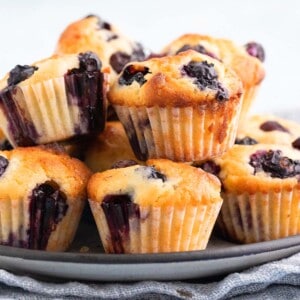 small blueberry muffins piled on a grey plate.