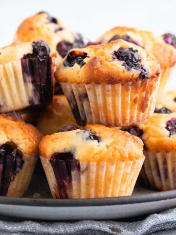 small blueberry muffins piled on a grey plate.