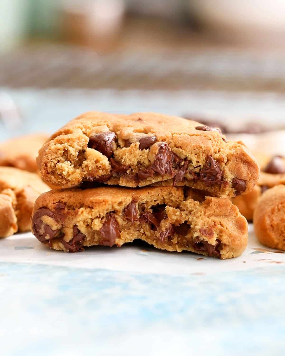 two halves of brown chocolate chip cookies on a blue board.