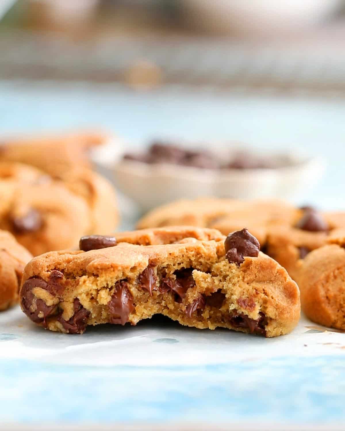 one half of brown chocolate chip cookies on a blue board.